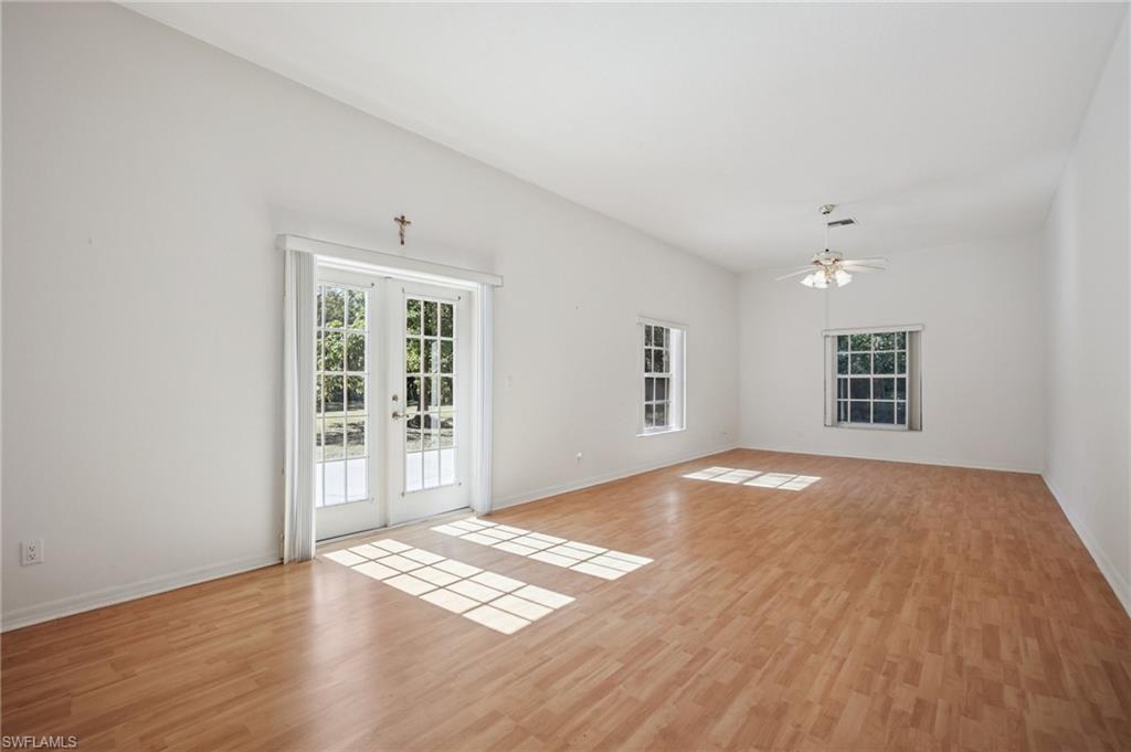 Unfurnished living room with French doors, light wood laminate flooring, and healthy amount of natural light