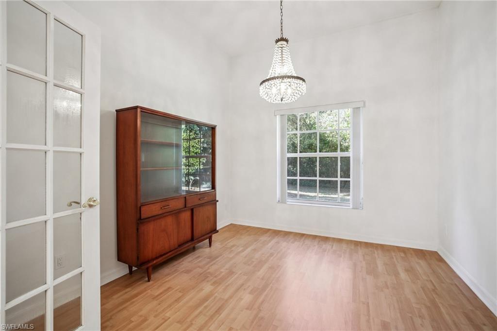 Other view of sitting area with suspended lighting, light wood laminate flooring, plenty of natural light, and a high ceiling