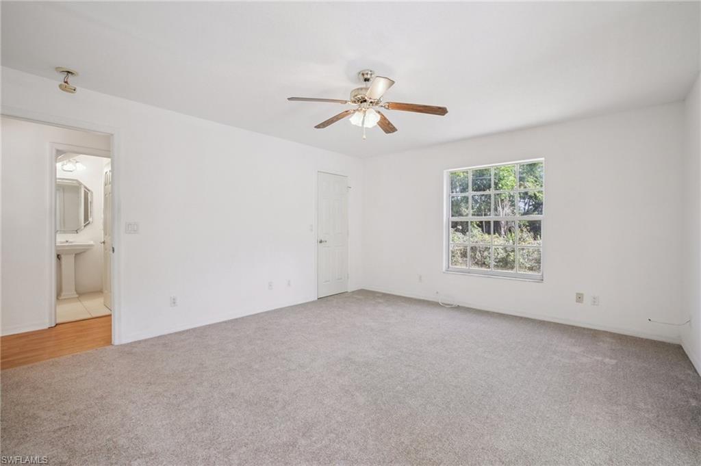 Another view of the primary bedroom featuring light colored carpet and ceiling fan