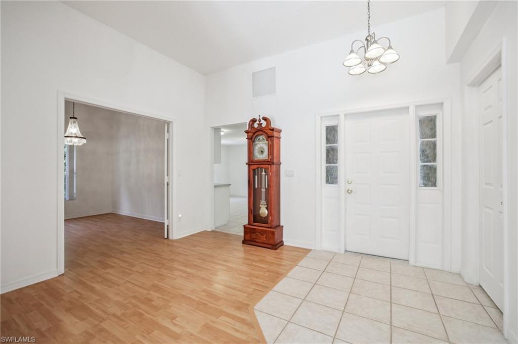Entryway featuring suspended lighting, light wood laminate flooring, and a high ceiling