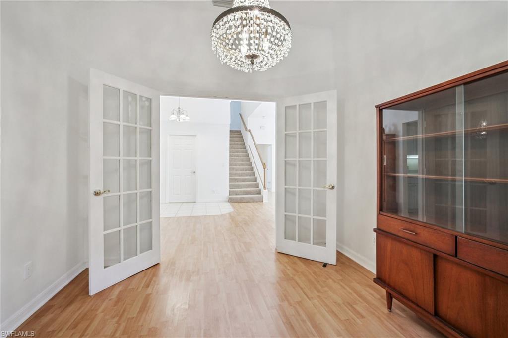 Sitting area featuring light wood laminate flooring, a chandelier, and French doors