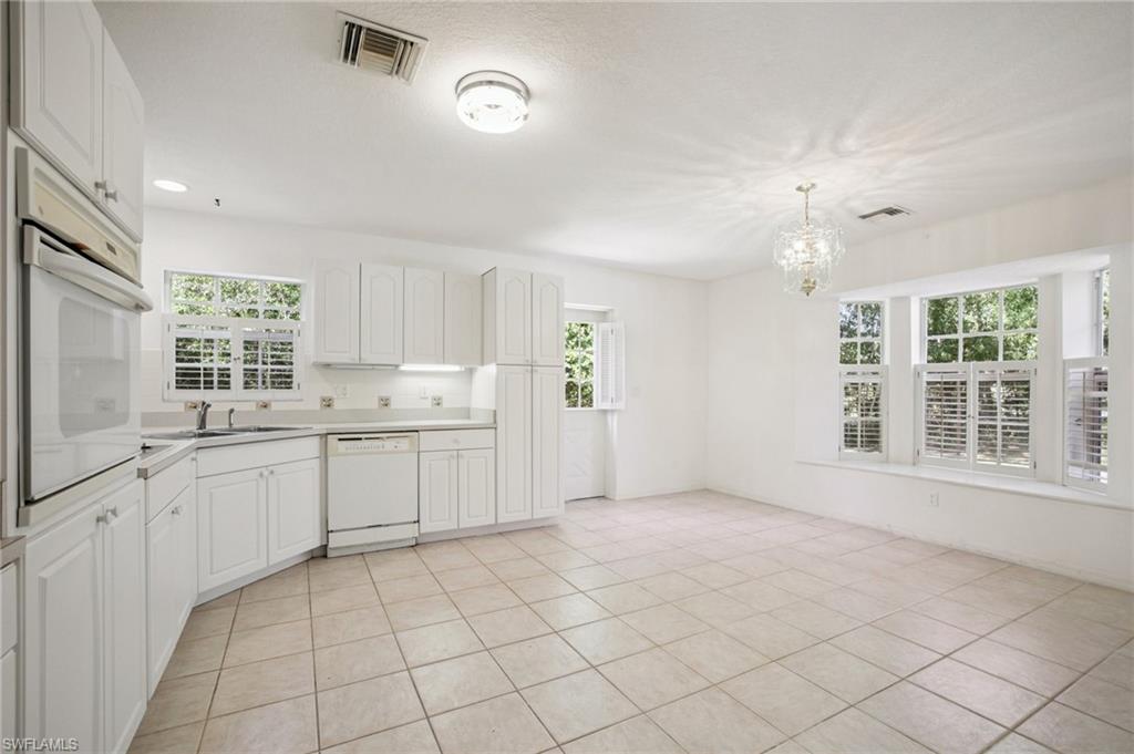 Kitchen with white cabinetry, white appliances, a chandelier, light countertops, and light tile patterned flooring