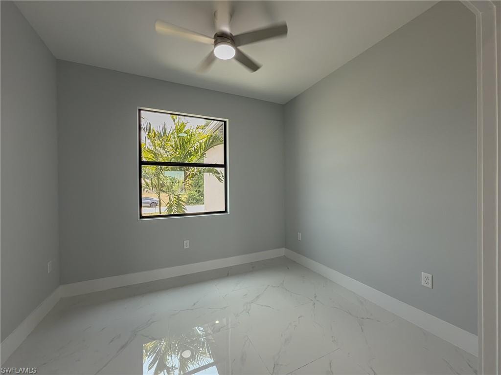 Den featuring marble finish floor, ceiling fan, and baseboards