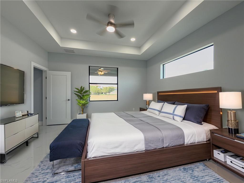 Bedroom with a ceiling fan, visible vents, marble finish floor, a tray ceiling, and recessed lighting