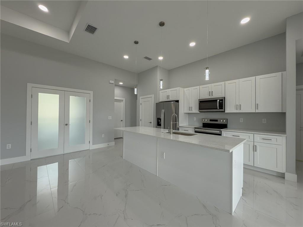 Kitchen with white cabinetry, stainless steel appliances, a sink, baseboards, and visible vents