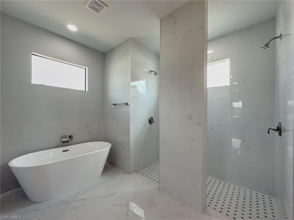 Full bath with marble finish floor, a marble finish shower, visible vents, and a soaking tub