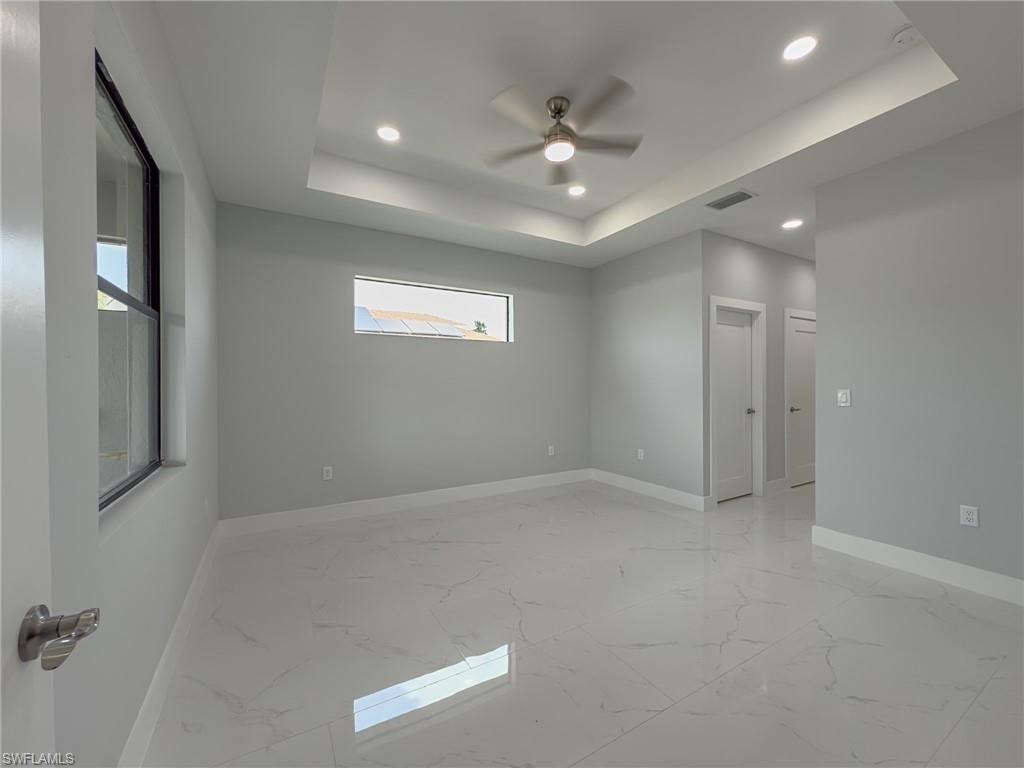 Unfurnished room with a raised ceiling, visible vents, baseboards, recessed lighting, and marble finish floor
