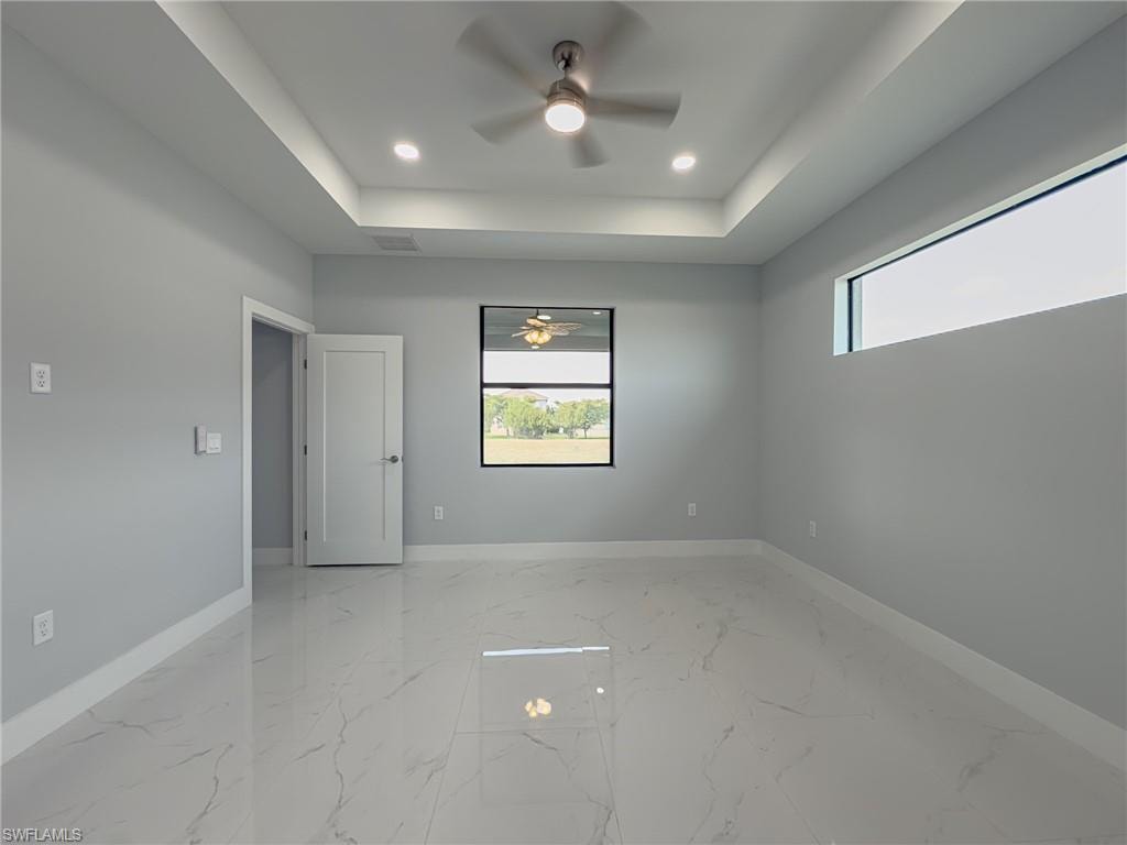 Unfurnished room with plenty of natural light, ceiling fan, and baseboards