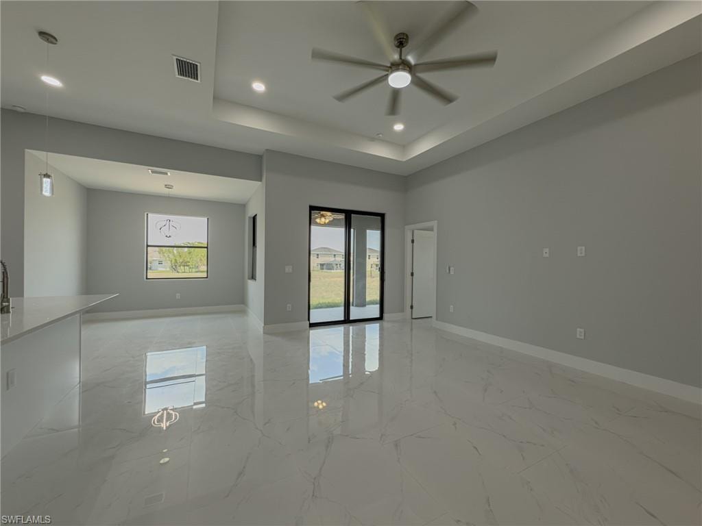 Empty room with visible vents, a ceiling fan, marble finish floor, and baseboards