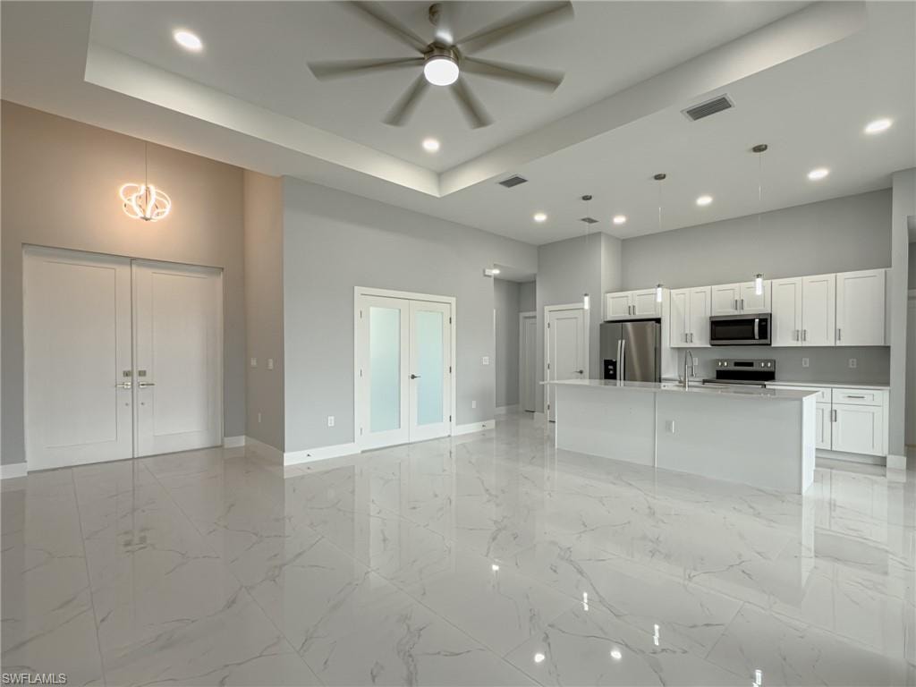 Unfurnished living room featuring recessed lighting, a sink, baseboards, visible vents, and a towering ceiling