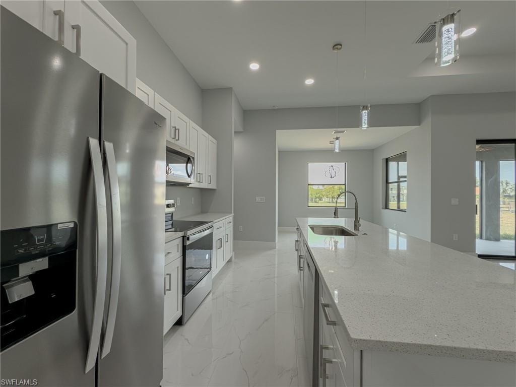 Kitchen featuring recessed lighting, a sink, a spacious island, marble finish floor, and appliances with stainless steel finishes