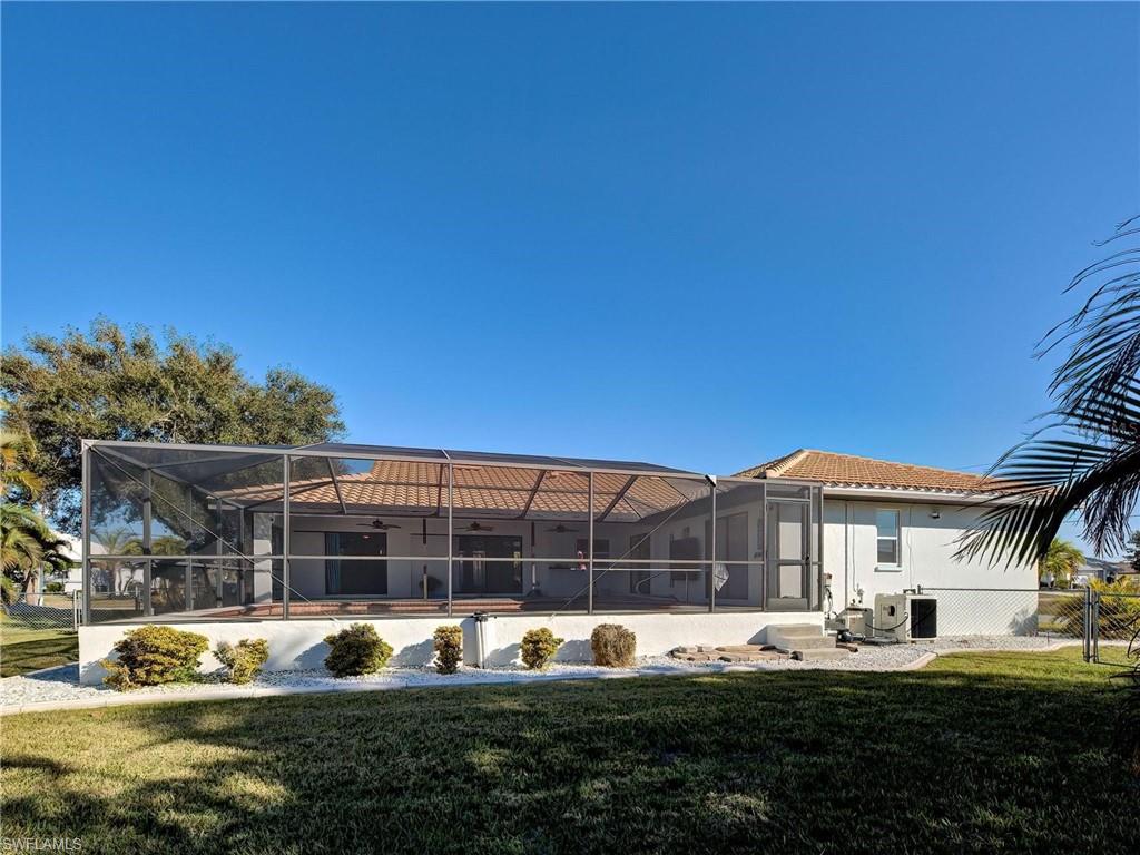Back of property with a sunroom, a lanai, a yard, and a tiled roof