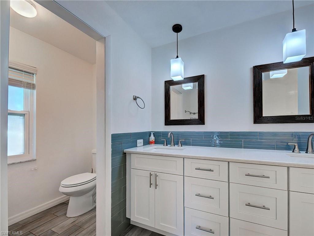 Bathroom featuring double vanity, tile walls, and wood tiled floors