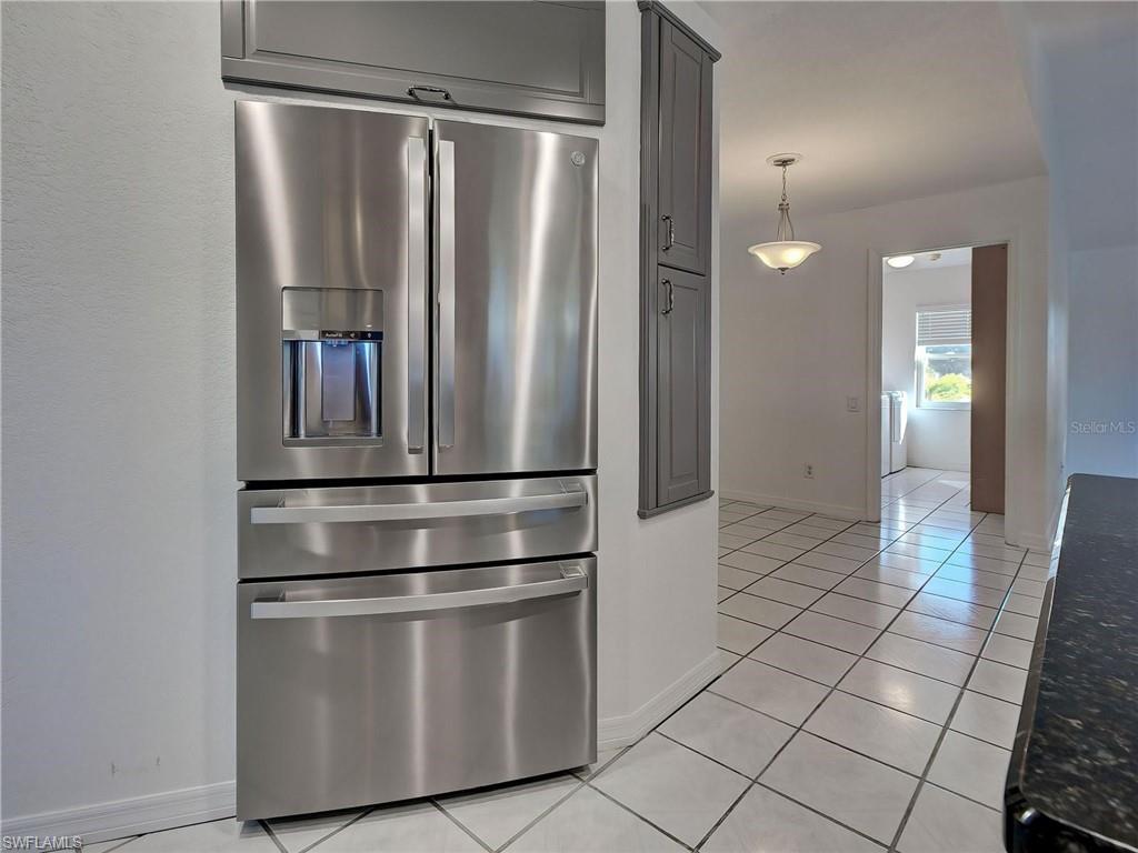 Kitchen with stainless steel refrigerator with ice dispenser, light tile patterned floors, and pendant lighting