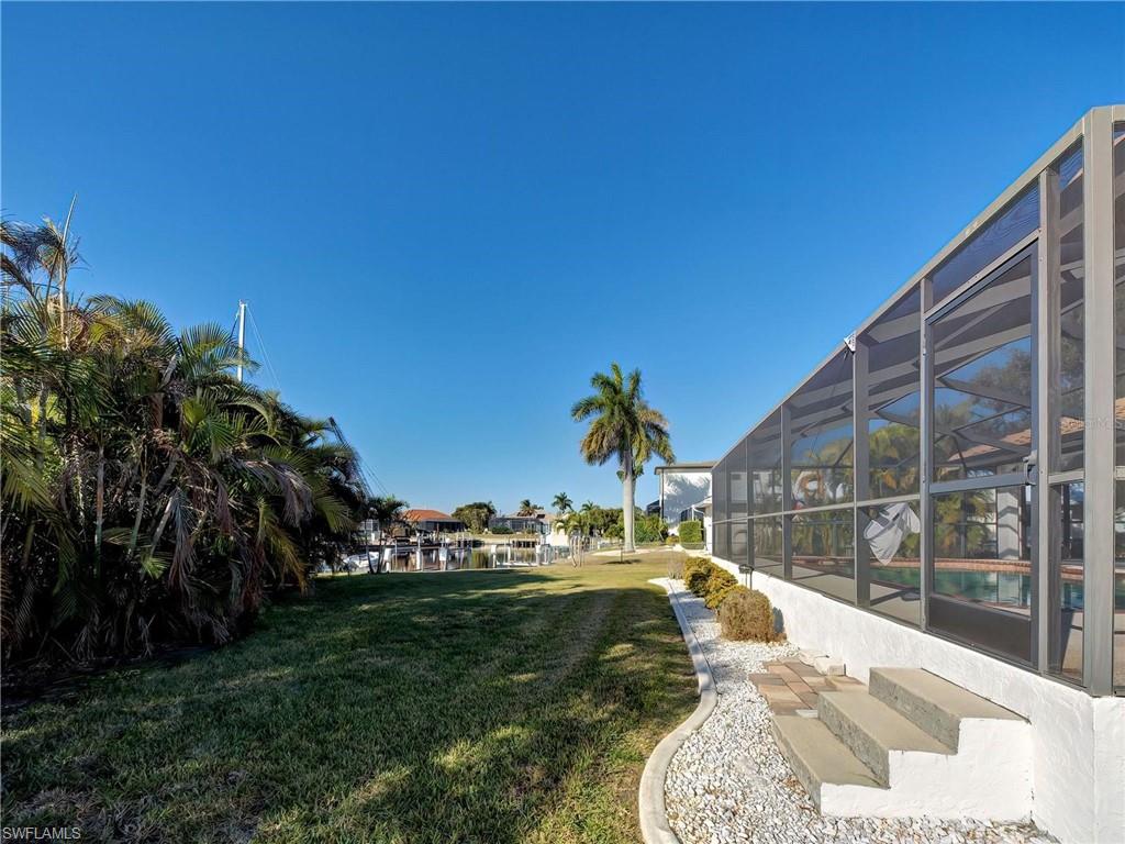 View of green lawn featuring glass enclosure and a sunroom