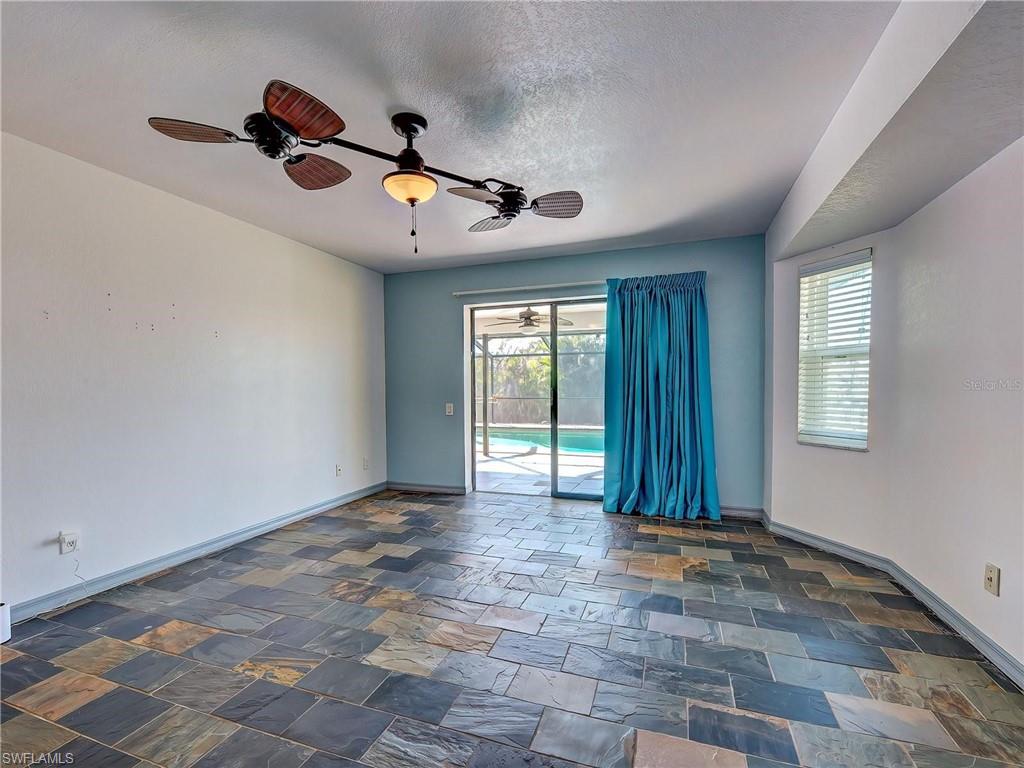 Spare room with dark stone finish flooring, a sunroom, ceiling fan, healthy amount of natural light, and a textured ceiling