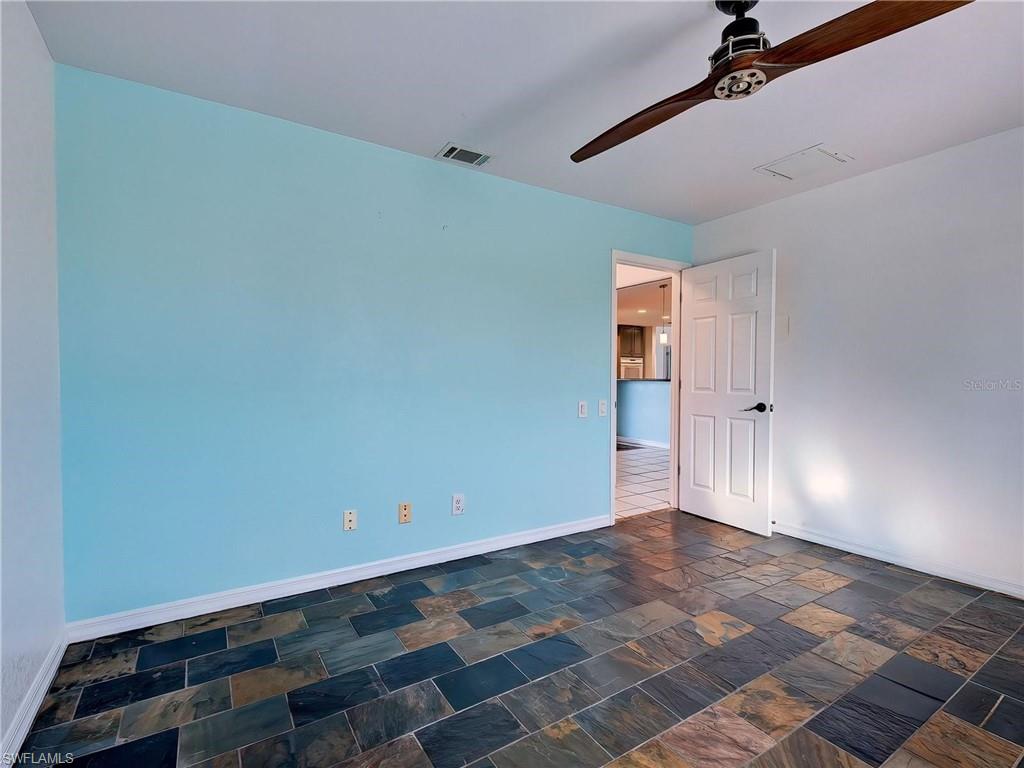 Empty room featuring a ceiling fan and dark stone finish flooring