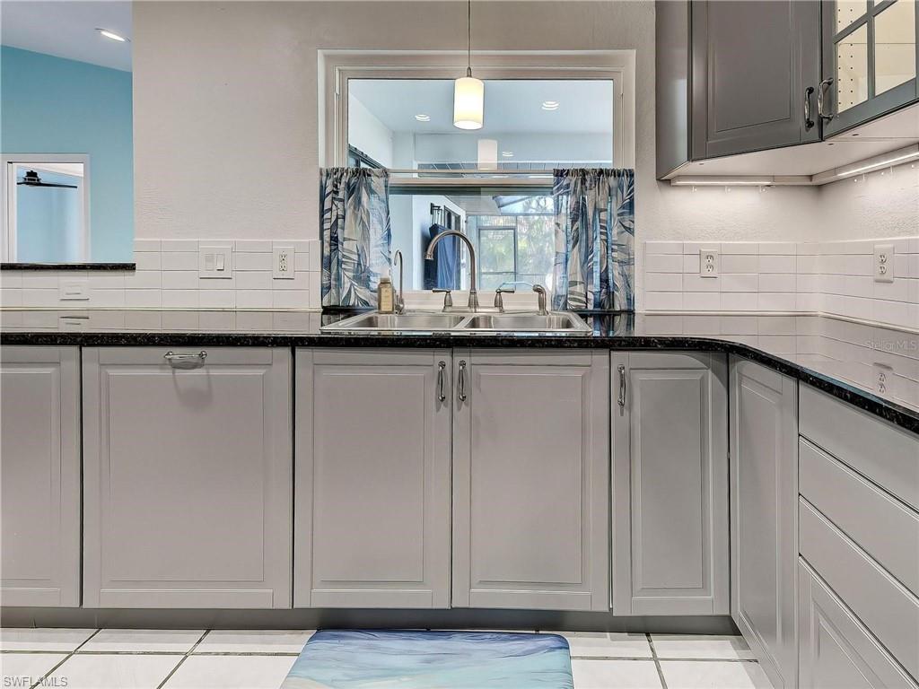 Kitchen with decorative light fixtures, dark stone counters, and a textured wall