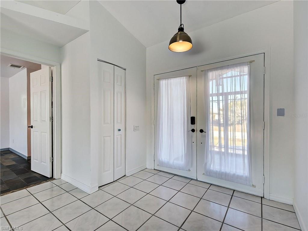 Entryway with lofted ceiling, french doors, and light tile patterned floors