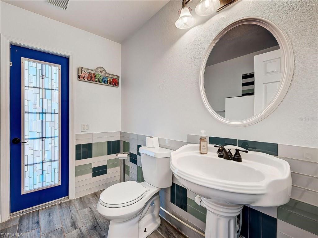 Half bathroom featuring wainscoting, wood finished floors, and tile walls