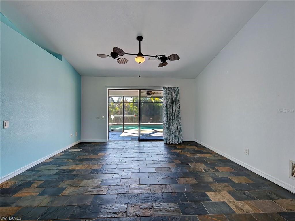 Spare room featuring a sunroom, a ceiling fan, and dark stone finish flooring