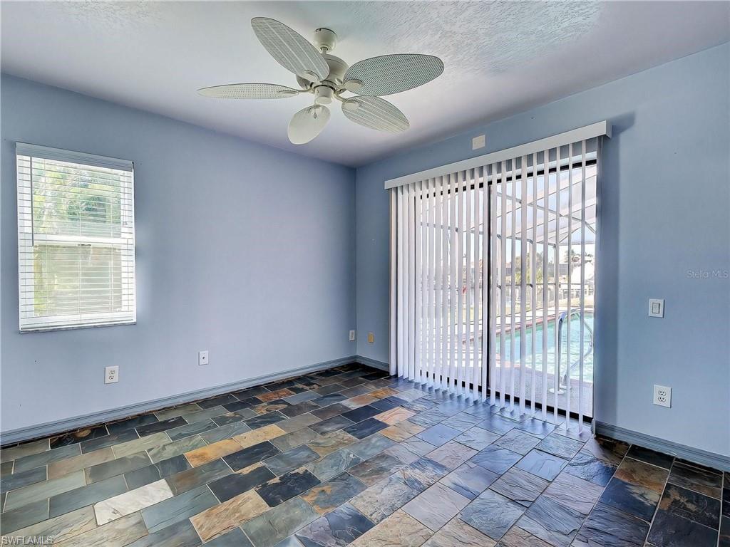 Empty room with a ceiling fan and stone tile floors