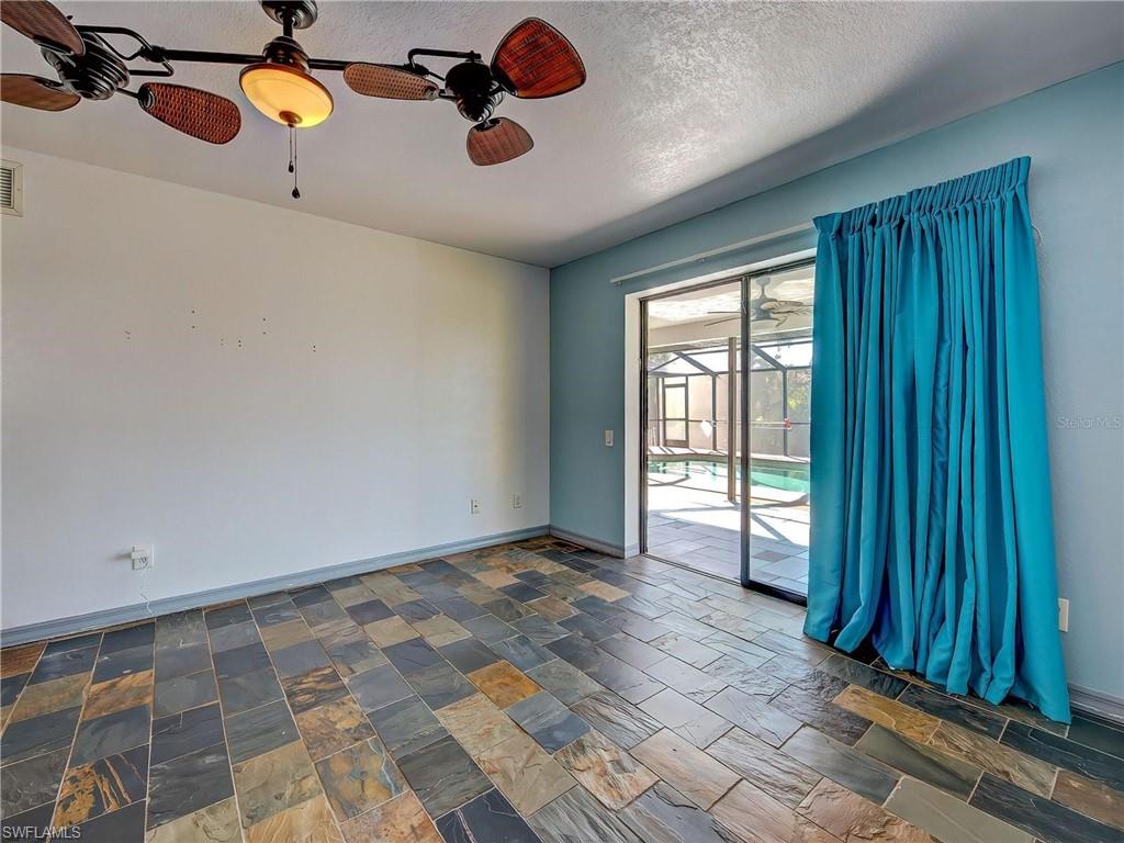 Empty room featuring a ceiling fan, stone tile floors, and a textured ceiling