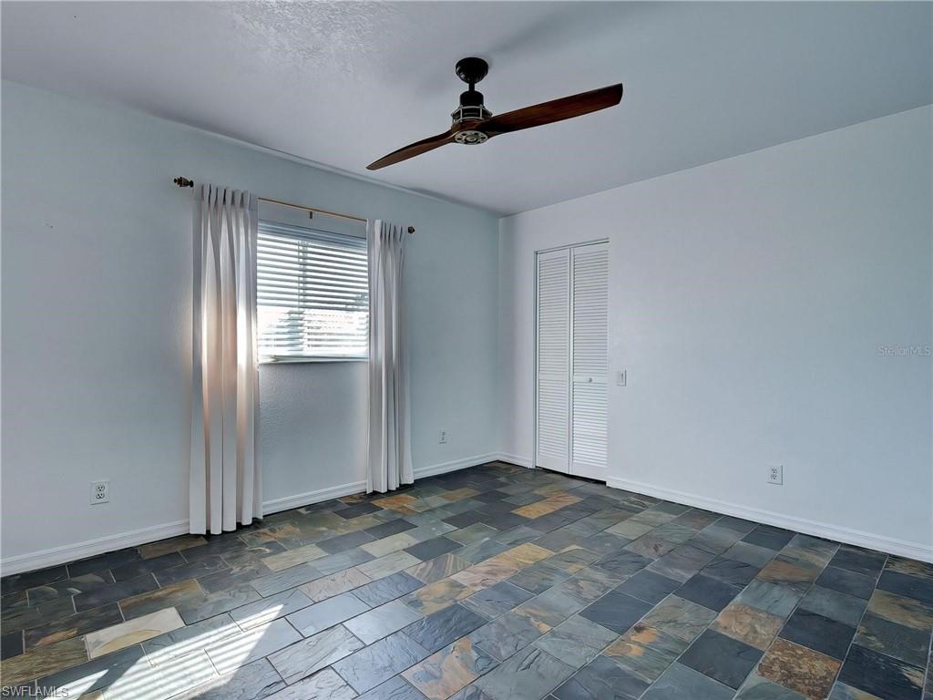 Empty room featuring stone tile flooring and a ceiling fan