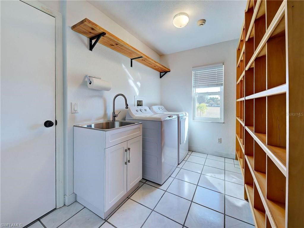 Laundry room with washing machine and clothes dryer and light tile patterned floors