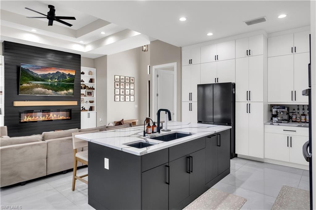 Kitchen featuring open floor plan, a center island with sink, modern cabinets, two tone cabinets, and a ceiling fan
