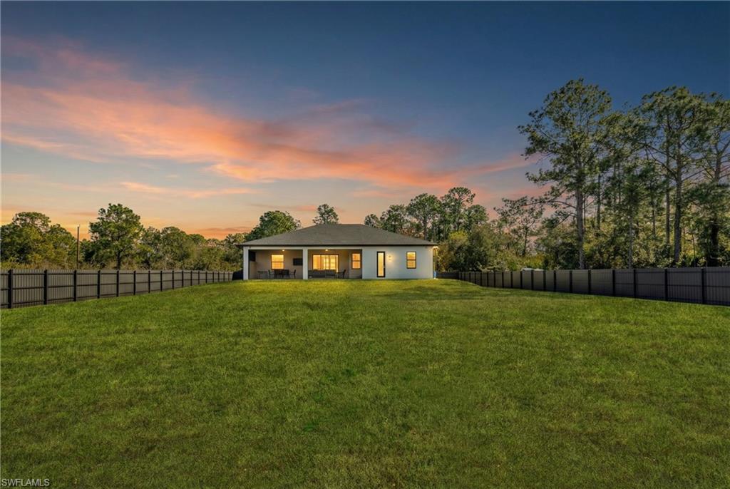 Back of house at dusk featuring a fenced backyard and a patio