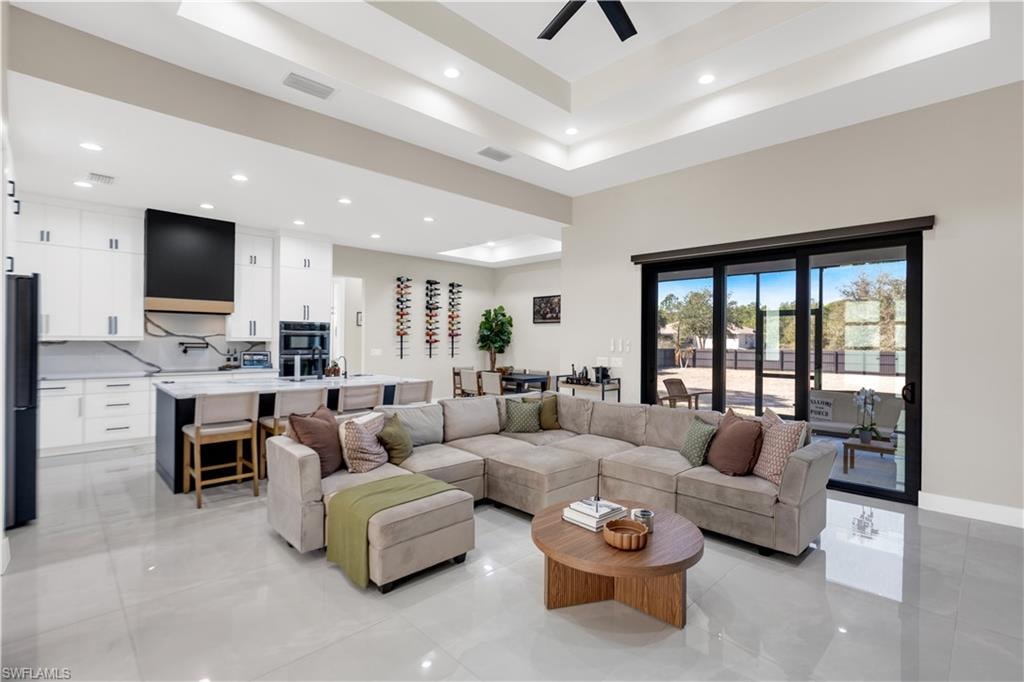 Living area with ceiling fan, a high tray ceiling, and recessed lighting