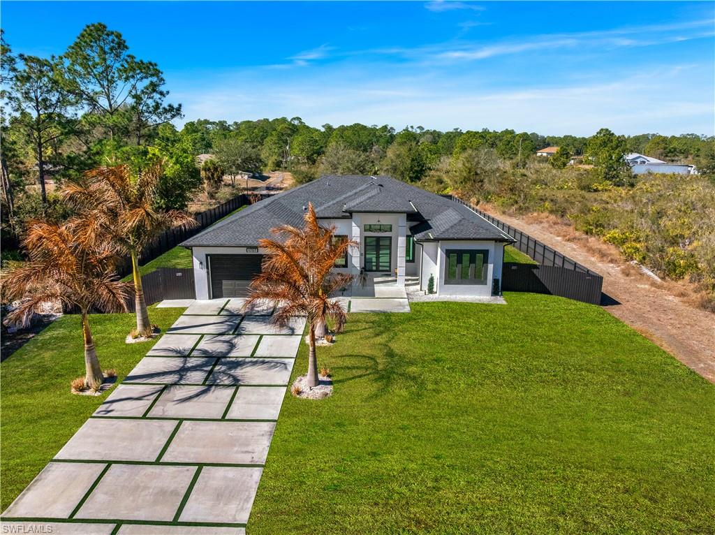 Back of property with concrete driveway, stucco siding, french doors, and a garage