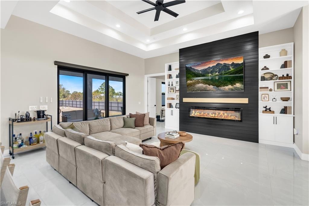 Living area featuring a high ceiling, a large fireplace, a ceiling fan, recessed lighting, and light tile patterned floors