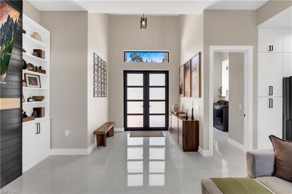 Entrance foyer featuring french doors, a high ceiling, and light tile patterned flooring