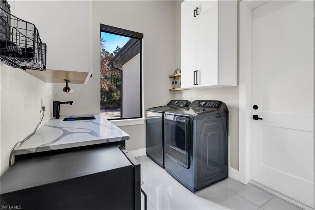 Laundry area with cabinet space, light tile patterned floors, and washing machine and dryer