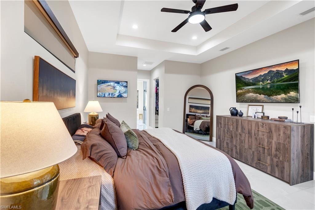 Bedroom with a raised ceiling, recessed lighting, and a ceiling fan