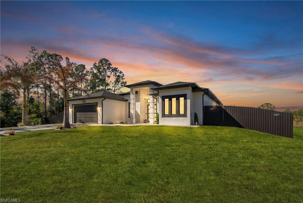 View of front facade featuring stucco siding, a garage, and driveway