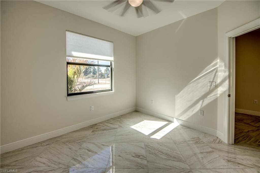 Empty room with ceiling fan and light marble finish floors