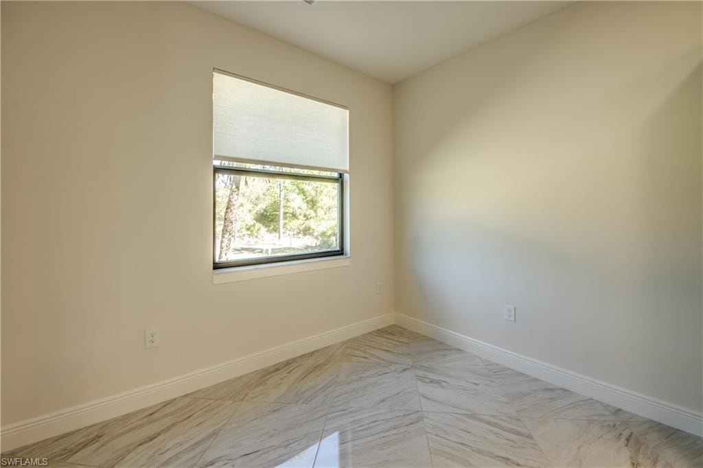 Unfurnished room with baseboards and light marble finish flooring