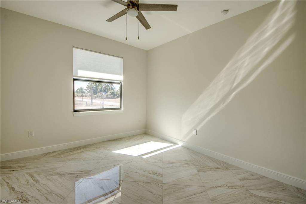 Empty room featuring light marble finish flooring and ceiling fan