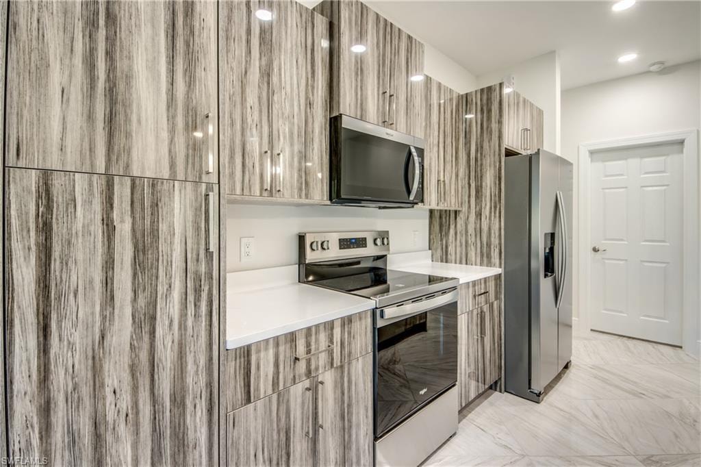 Kitchen featuring modern cabinets, stainless steel appliances, and light stone counters
