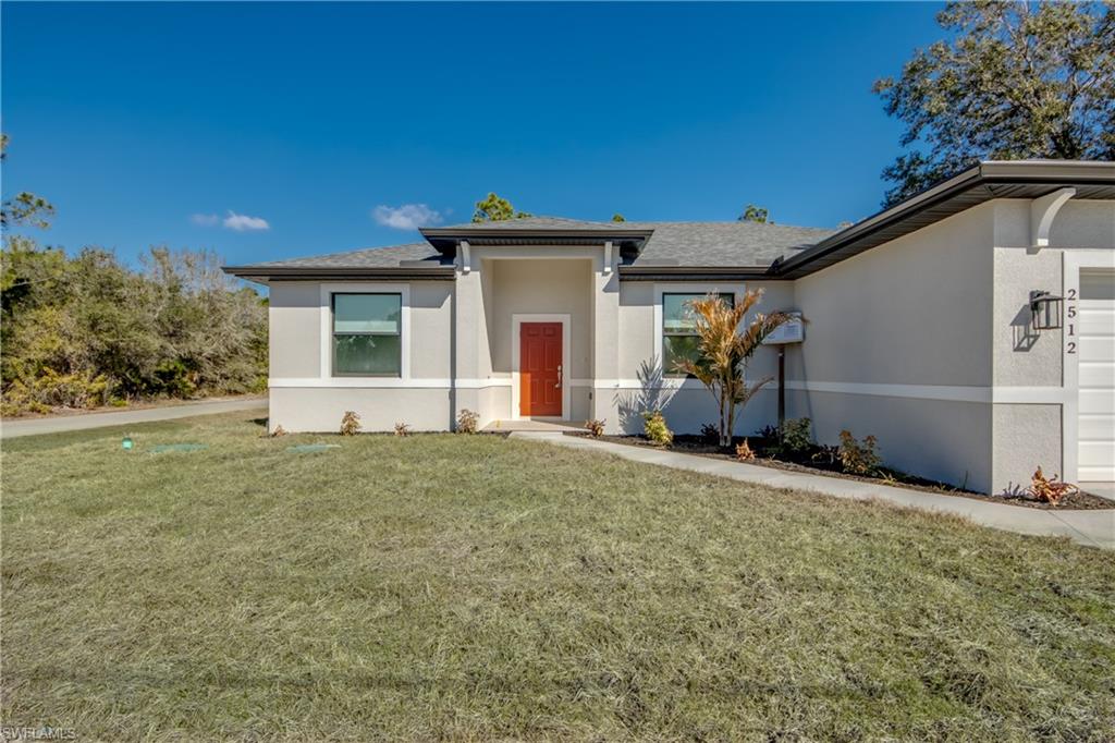 View of front of property featuring stucco siding, a front lawn, a shingled roof, and an attached garage