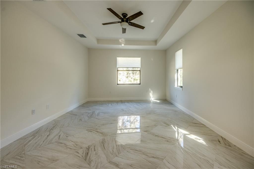 Spare room with a raised ceiling and ceiling fan