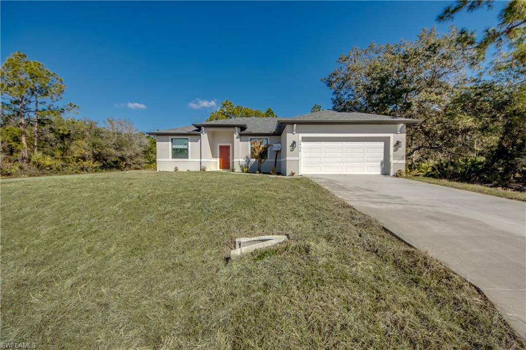 Prairie-style house with stucco siding, a front lawn, concrete driveway, and an attached garage