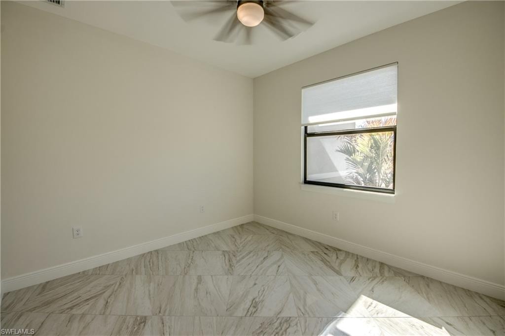 Unfurnished room featuring ceiling fan and light marble finish flooring