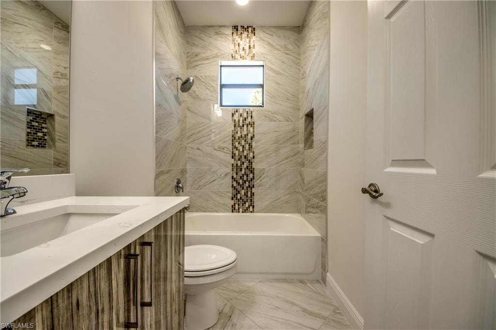 Bathroom featuring bathtub / shower combination, vanity, and light marble finish flooring