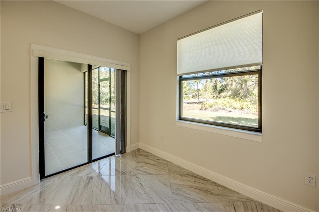 Unfurnished room featuring baseboards and light marble finish flooring