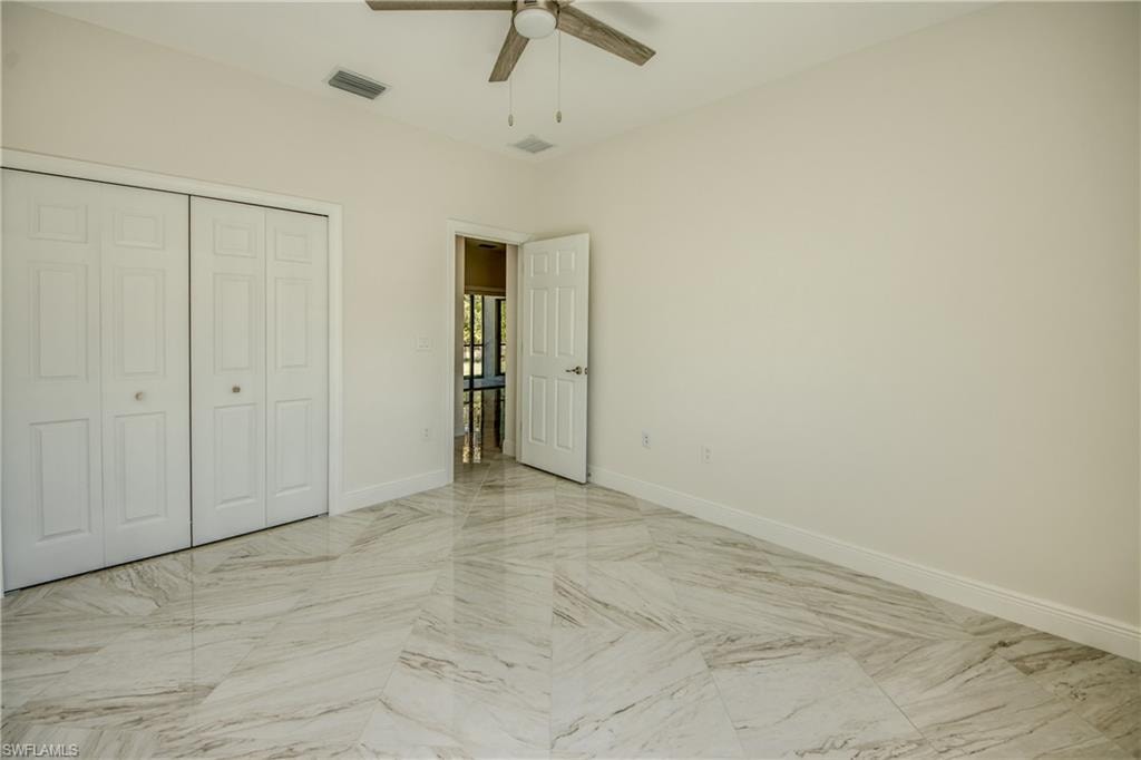 Unfurnished bedroom with ceiling fan, a closet, and light marble finish flooring