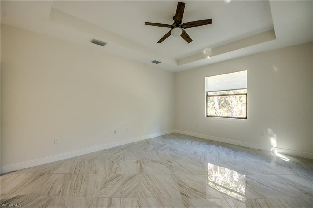 Empty room with a tray ceiling and ceiling fan
